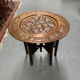 Middle eastern carved folding bases coffee table. It has a copper top intricately pierced and patterned. It is in good original condition. Please see photos as they form part of the description and condition.