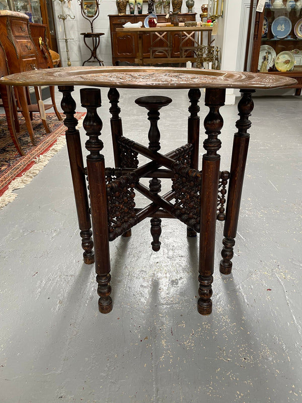 Middle eastern carved folding bases coffee table. It has a copper top intricately pierced and patterned. It is in good original condition. Please see photos as they form part of the description and condition.