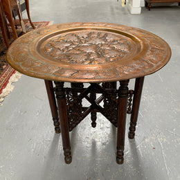 Middle eastern carved folding bases coffee table. It has a copper top intricately pierced and patterned. It is in good original condition. Please see photos as they form part of the description and condition.