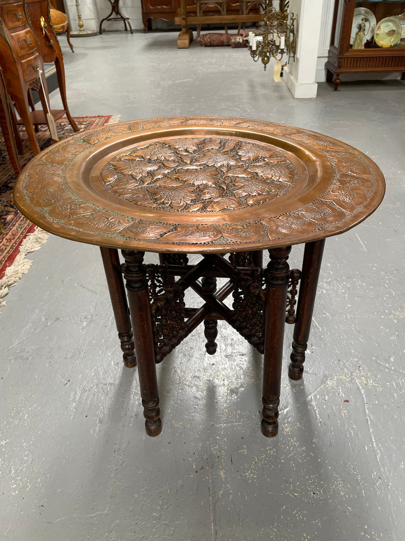 Middle eastern carved folding bases coffee table. It has a copper top intricately pierced and patterned. It is in good original condition. Please see photos as they form part of the description and condition.