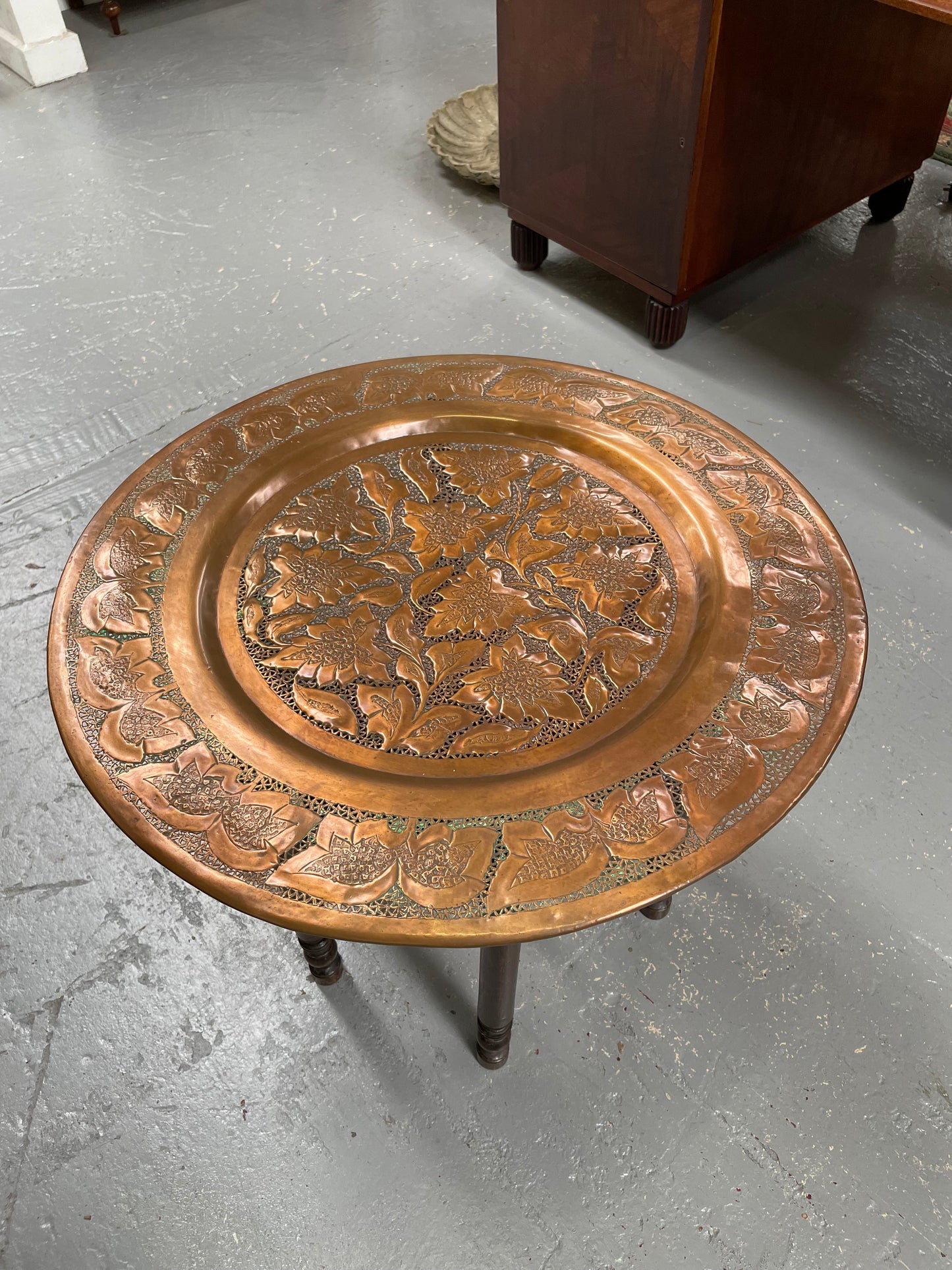 Middle eastern carved folding bases coffee table. It has a copper top intricately pierced and patterned. It is in good original condition. Please see photos as they form part of the description and condition.