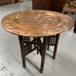 Middle eastern carved folding bases coffee table. It has a copper top intricately pierced and patterned. It is in good original condition. Please see photos as they form part of the description and condition.
