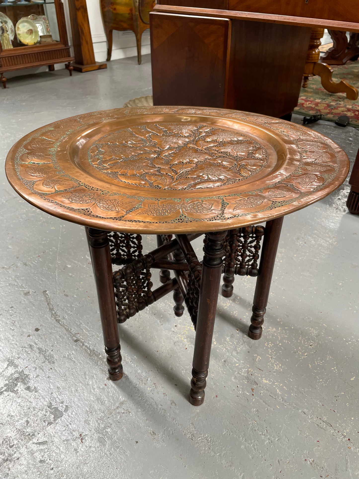 Middle eastern carved folding bases coffee table. It has a copper top intricately pierced and patterned. It is in good original condition. Please see photos as they form part of the description and condition.