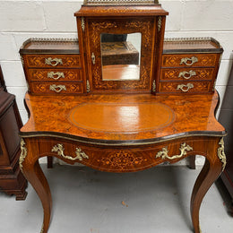 A very attractive burr walnut writing desk (Bonheur De Jour) with ormolu mounts throughout. The boxwood inlaid decoration is featured on the drawers and the mirrored cupboard which also feature brass galleries. The table area features burr walnut and a tooled leather inlay. A long drawer underneath features further inlay and stringing and all have lovely ormolu handles. It is a stunning piece of furniture of fantastic quality and makes a good ladies writing desk. In very good condition.