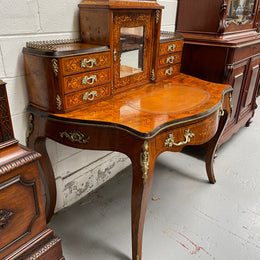 A very attractive burr walnut writing desk (Bonheur De Jour) with ormolu mounts throughout. The boxwood inlaid decoration is featured on the drawers and the mirrored cupboard which also feature brass galleries. The table area features burr walnut and a tooled leather inlay. A long drawer underneath features further inlay and stringing and all have lovely ormolu handles. It is a stunning piece of furniture of fantastic quality and makes a good ladies writing desk. In very good condition.
