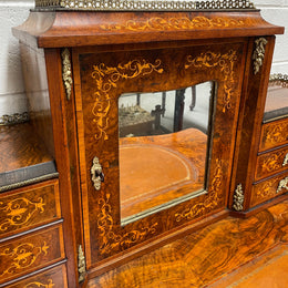 A very attractive burr walnut writing desk (Bonheur De Jour) with ormolu mounts throughout. The boxwood inlaid decoration is featured on the drawers and the mirrored cupboard which also feature brass galleries. The table area features burr walnut and a tooled leather inlay. A long drawer underneath features further inlay and stringing and all have lovely ormolu handles. It is a stunning piece of furniture of fantastic quality and makes a good ladies writing desk. In very good condition.