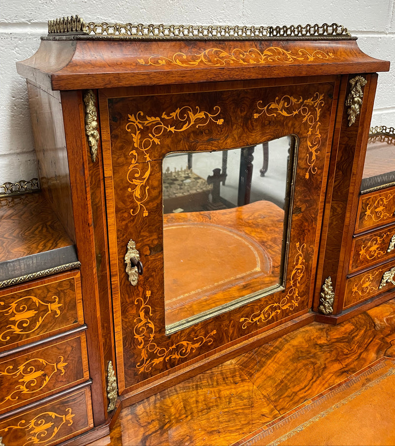 A very attractive burr walnut writing desk (Bonheur De Jour) with ormolu mounts throughout. The boxwood inlaid decoration is featured on the drawers and the mirrored cupboard which also feature brass galleries. The table area features burr walnut and a tooled leather inlay. A long drawer underneath features further inlay and stringing and all have lovely ormolu handles. It is a stunning piece of furniture of fantastic quality and makes a good ladies writing desk. In very good condition.