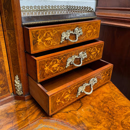 A very attractive burr walnut writing desk (Bonheur De Jour) with ormolu mounts throughout. The boxwood inlaid decoration is featured on the drawers and the mirrored cupboard which also feature brass galleries. The table area features burr walnut and a tooled leather inlay. A long drawer underneath features further inlay and stringing and all have lovely ormolu handles. It is a stunning piece of furniture of fantastic quality and makes a good ladies writing desk. In very good condition.