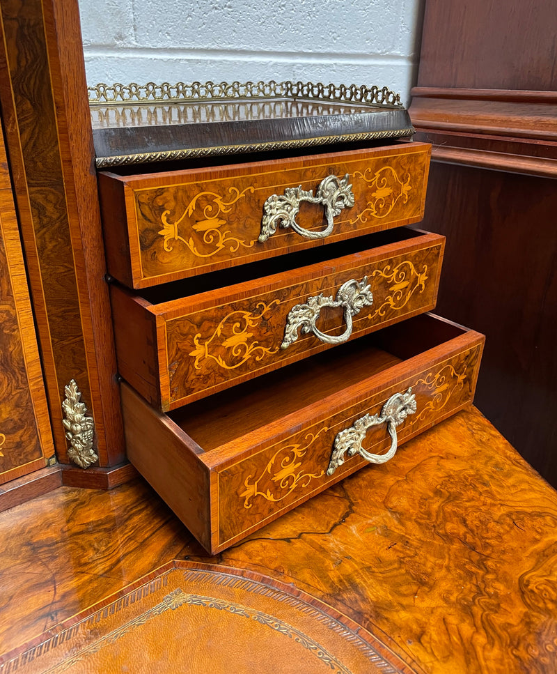A very attractive burr walnut writing desk (Bonheur De Jour) with ormolu mounts throughout. The boxwood inlaid decoration is featured on the drawers and the mirrored cupboard which also feature brass galleries. The table area features burr walnut and a tooled leather inlay. A long drawer underneath features further inlay and stringing and all have lovely ormolu handles. It is a stunning piece of furniture of fantastic quality and makes a good ladies writing desk. In very good condition.