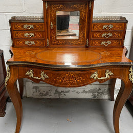 A very attractive burr walnut writing desk (Bonheur De Jour) with ormolu mounts throughout. The boxwood inlaid decoration is featured on the drawers and the mirrored cupboard which also feature brass galleries. The table area features burr walnut and a tooled leather inlay. A long drawer underneath features further inlay and stringing and all have lovely ormolu handles. It is a stunning piece of furniture of fantastic quality and makes a good ladies writing desk. In very good condition.