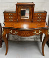 A very attractive burr walnut writing desk (Bonheur De Jour) with ormolu mounts throughout. The boxwood inlaid decoration is featured on the drawers and the mirrored cupboard which also feature brass galleries. The table area features burr walnut and a tooled leather inlay. A long drawer underneath features further inlay and stringing and all have lovely ormolu handles. It is a stunning piece of furniture of fantastic quality and makes a good ladies writing desk. In very good condition.