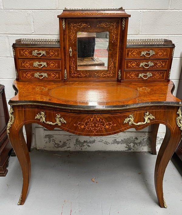 A very attractive burr walnut writing desk (Bonheur De Jour) with ormolu mounts throughout. The boxwood inlaid decoration is featured on the drawers and the mirrored cupboard which also feature brass galleries. The table area features burr walnut and a tooled leather inlay. A long drawer underneath features further inlay and stringing and all have lovely ormolu handles. It is a stunning piece of furniture of fantastic quality and makes a good ladies writing desk. In very good condition.