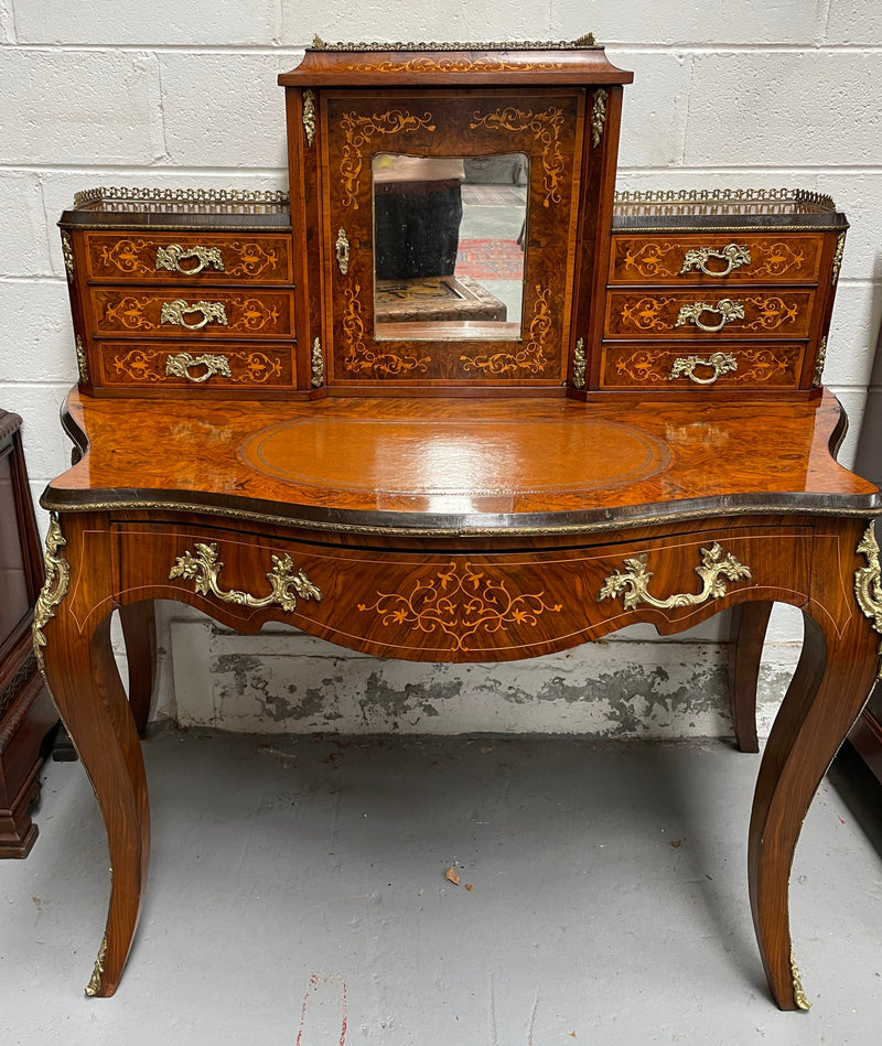 A very attractive burr walnut writing desk (Bonheur De Jour) with ormolu mounts throughout. The boxwood inlaid decoration is featured on the drawers and the mirrored cupboard which also feature brass galleries. The table area features burr walnut and a tooled leather inlay. A long drawer underneath features further inlay and stringing and all have lovely ormolu handles. It is a stunning piece of furniture of fantastic quality and makes a good ladies writing desk. In very good condition.