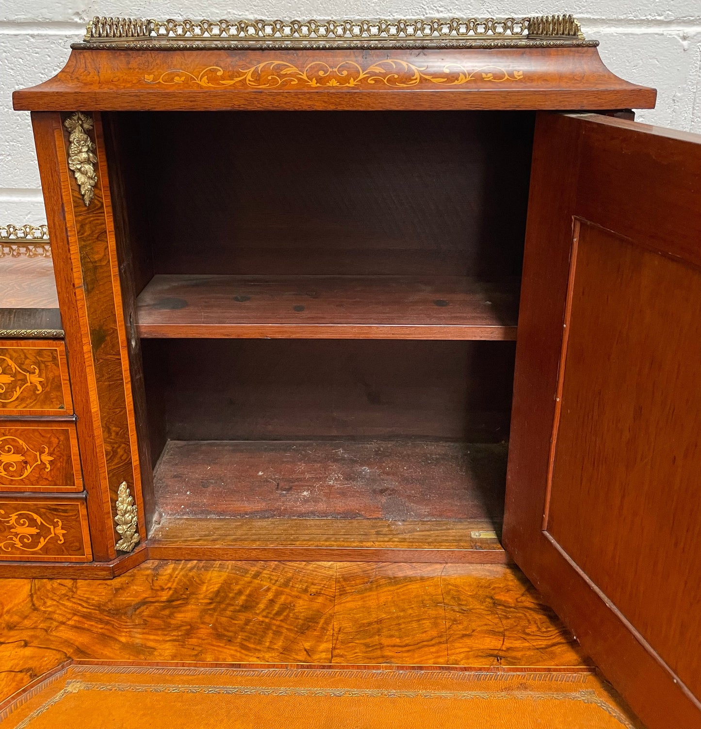 A very attractive burr walnut writing desk (Bonheur De Jour) with ormolu mounts throughout. The boxwood inlaid decoration is featured on the drawers and the mirrored cupboard which also feature brass galleries. The table area features burr walnut and a tooled leather inlay. A long drawer underneath features further inlay and stringing and all have lovely ormolu handles. It is a stunning piece of furniture of fantastic quality and makes a good ladies writing desk. In very good condition.