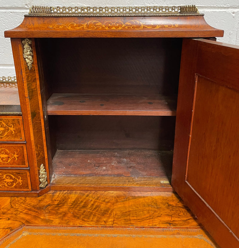 A very attractive burr walnut writing desk (Bonheur De Jour) with ormolu mounts throughout. The boxwood inlaid decoration is featured on the drawers and the mirrored cupboard which also feature brass galleries. The table area features burr walnut and a tooled leather inlay. A long drawer underneath features further inlay and stringing and all have lovely ormolu handles. It is a stunning piece of furniture of fantastic quality and makes a good ladies writing desk. In very good condition.