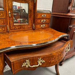 A very attractive burr walnut writing desk (Bonheur De Jour) with ormolu mounts throughout. The boxwood inlaid decoration is featured on the drawers and the mirrored cupboard which also feature brass galleries. The table area features burr walnut and a tooled leather inlay. A long drawer underneath features further inlay and stringing and all have lovely ormolu handles. It is a stunning piece of furniture of fantastic quality and makes a good ladies writing desk. In very good condition.
