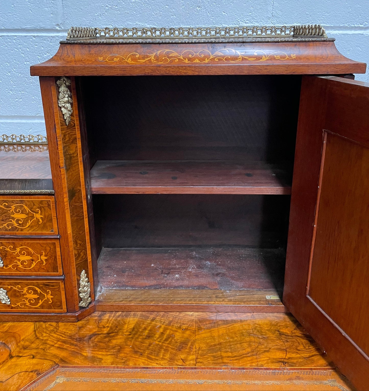 A very attractive burr walnut writing desk (Bonheur De Jour) with ormolu mounts throughout. The boxwood inlaid decoration is featured on the drawers and the mirrored cupboard which also feature brass galleries. The table area features burr walnut and a tooled leather inlay. A long drawer underneath features further inlay and stringing and all have lovely ormolu handles. It is a stunning piece of furniture of fantastic quality and makes a good ladies writing desk. In very good condition.