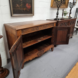 Vintage wooden cabinet with open door in a room with white walls and framed artwork.