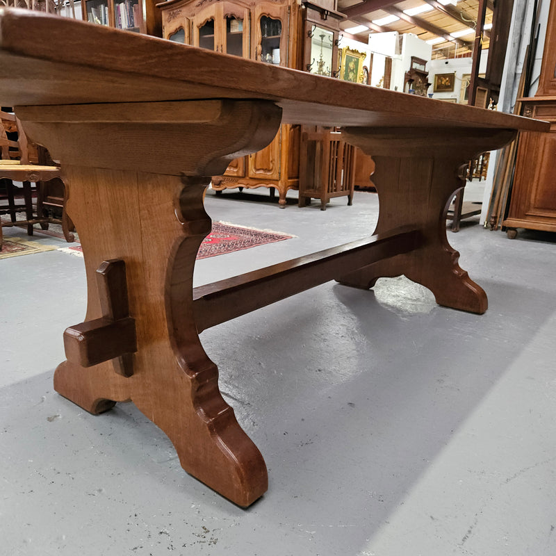 Stunning French oak monastery dining table. The top is supported on a large trestle base, and united with a single stretcher secured at each end with oak pegs. Sourced directly from France and is in good restored condition. It can seat 6-8 people comfortably.