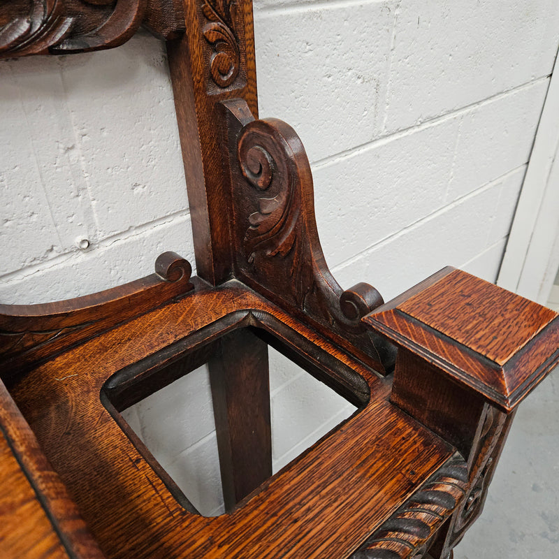 Stunning English Oak gothic style hallstand with one drawer, mirror and 6 hooks and two compartments for umbrellas. It is beautifully decorated and carved. It is in good original detailed condition. 