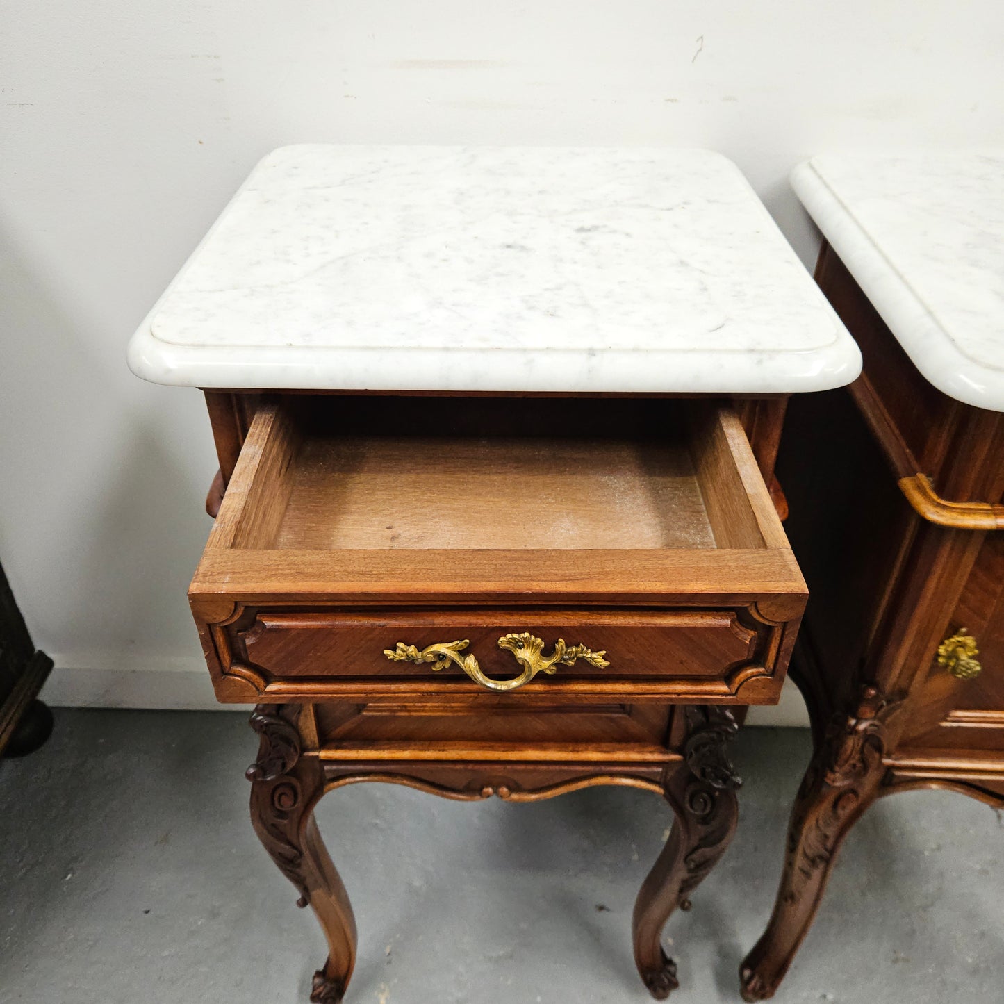 Pair of French Walnut Louis XV Style white marble top bedside cabinets. Featuring beautiful parquetry work and decorative carvings throughout. Sourced directly from France and in good original detailed condition.