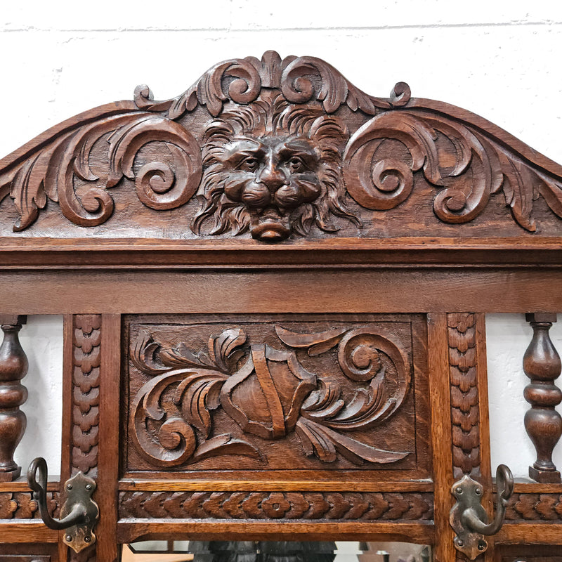 Stunning English Oak gothic style hallstand with one drawer, mirror and 6 hooks and two compartments for umbrellas. It is beautifully decorated and carved. It is in good original detailed condition. 