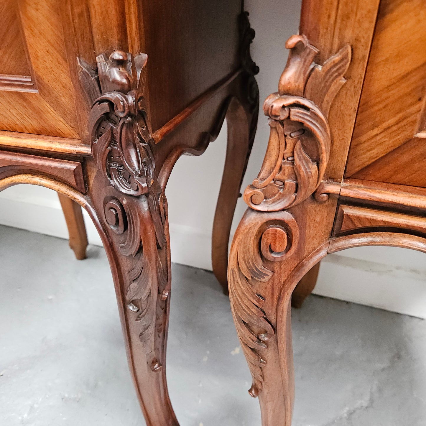 Pair of French Walnut Louis XV Style white marble top bedside cabinets. Featuring beautiful parquetry work and decorative carvings throughout. Sourced directly from France and in good original detailed condition.