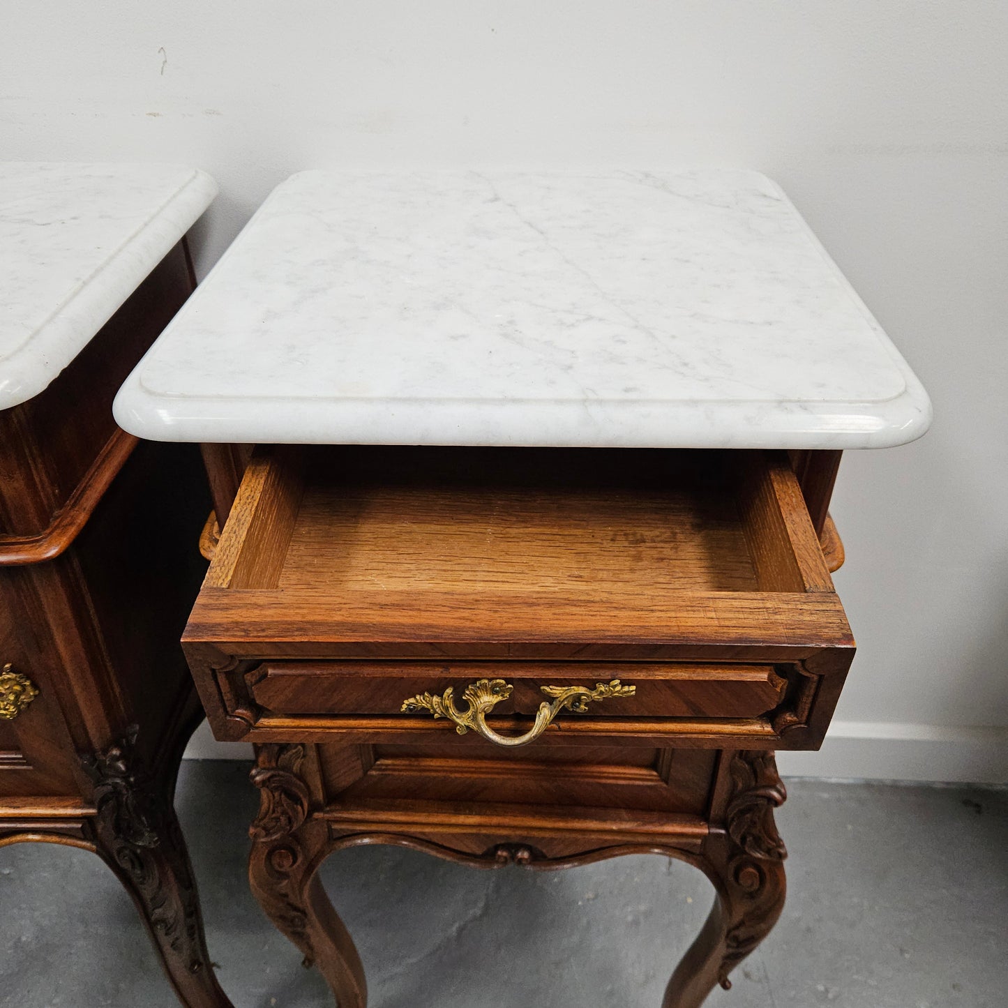 Pair of French Walnut Louis XV Style white marble top bedside cabinets. Featuring beautiful parquetry work and decorative carvings throughout. Sourced directly from France and in good original detailed condition.