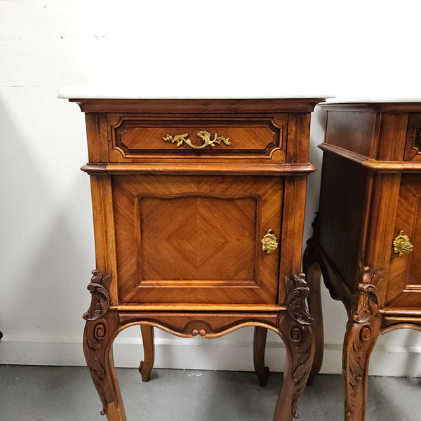 Pair of French Walnut Louis XV Style white marble top bedside cabinets. Featuring beautiful parquetry work and decorative carvings throughout. Sourced directly from France and in good original detailed condition.