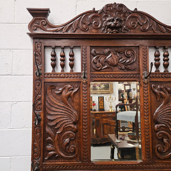 Stunning English Oak gothic style hallstand with one drawer, mirror and 6 hooks and two compartments for umbrellas. It is beautifully decorated and carved. It is in good original detailed condition. 