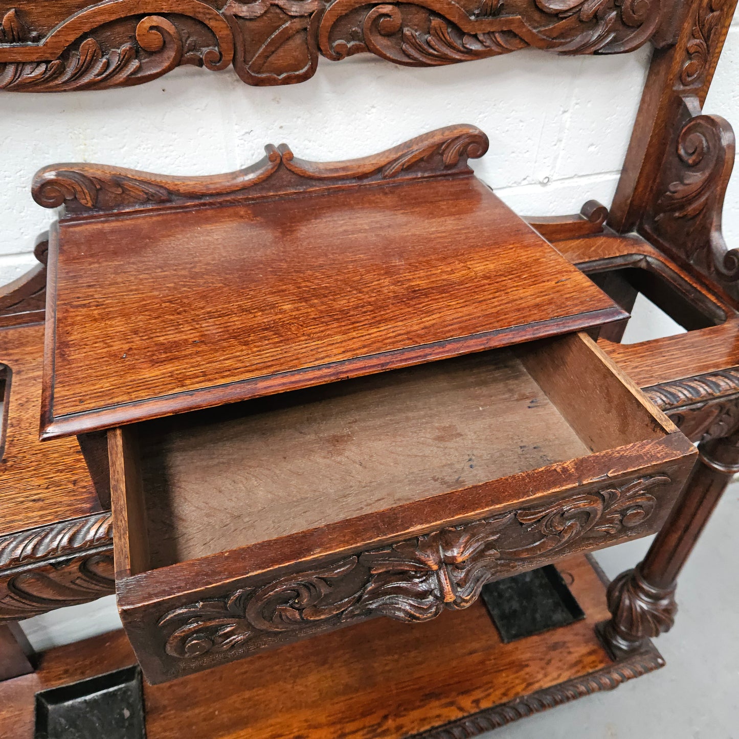 Stunning English Oak gothic style hallstand with one drawer, mirror and 6 hooks and two compartments for umbrellas. It is beautifully decorated and carved. It is in good original detailed condition. 