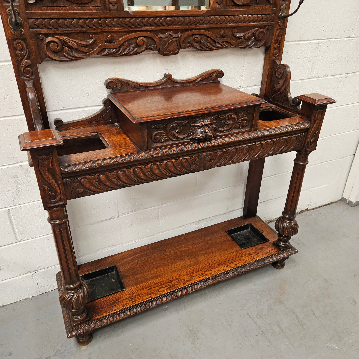 Stunning English Oak gothic style hallstand with one drawer, mirror and 6 hooks and two compartments for umbrellas. It is beautifully decorated and carved. It is in good original detailed condition. 