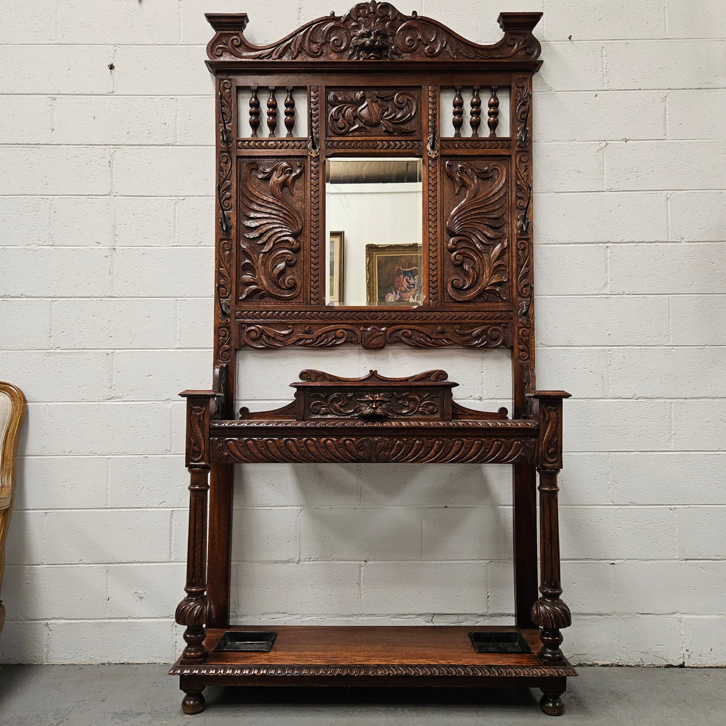 Stunning English Oak gothic style hallstand with one drawer, mirror and 6 hooks and two compartments for umbrellas. It is beautifully decorated and carved. It is in good original detailed condition. 