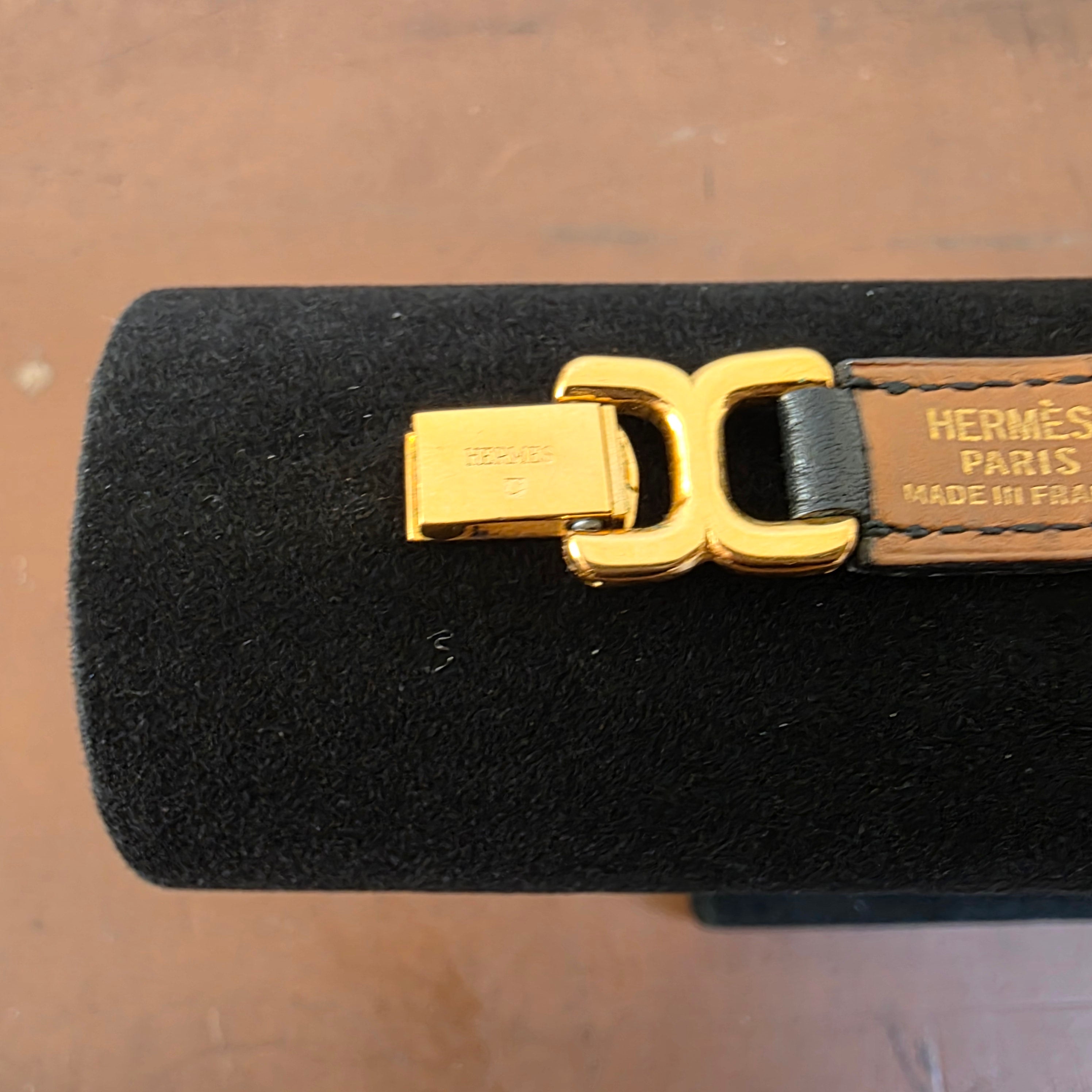 Detailed view of the gold-plated clasp and stamped black leather section