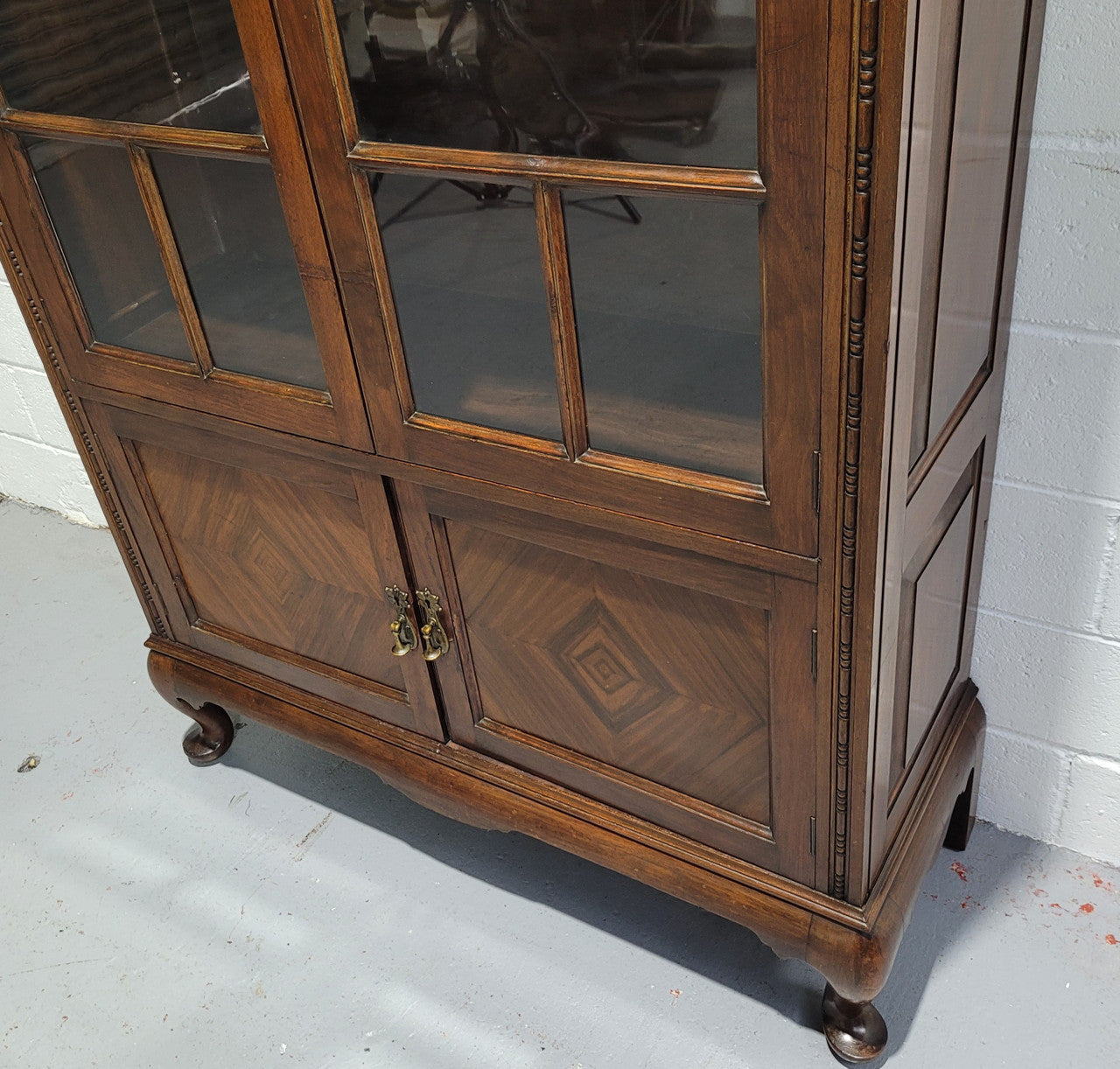 English Walnut two door bookcase with original glass. It has three adjustable shelves and hidden storage below behind two smaller doors. It is in food original condition.