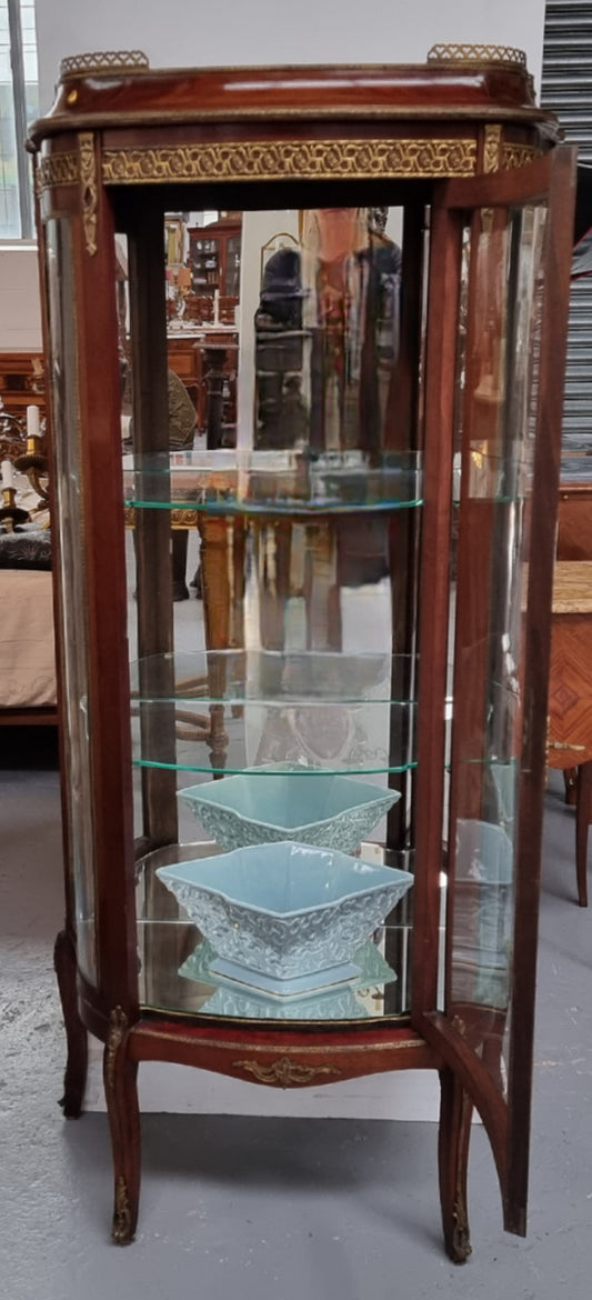 Beautiful French Louis XV style vitrine/ display cabinet with curved glass, gilt mounts, mirrored back and two glass shelves for your displays . It is in good original detailed condition.
