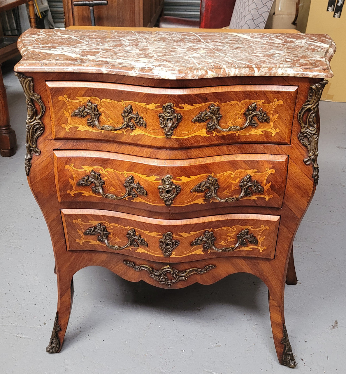 Antique French Louis XV style compact three drawer marble top commode with marquetry inlay and ormolu mounts. Sourced from France and in good original detailed condition.
