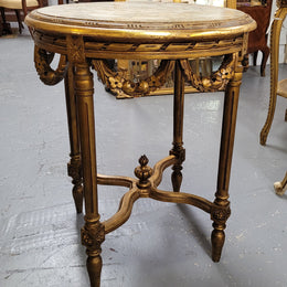 French Louis XVI style round marble topped gilded lamp/side table featuring lovely carved swags and undercarriage. It has been sourced from France and is in good original detailed condition.