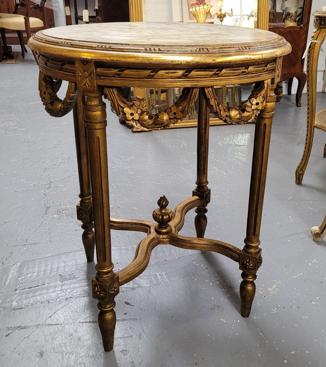 French Louis XVI style round marble topped gilded lamp/side table featuring lovely carved swags and undercarriage. It has been sourced from France and is in good original detailed condition.