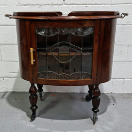 Oak Tudor auto trolley with beautiful leadlight glass. It is on wheels and the door open up to a cabinet with one shelf. In good original detailed condition.