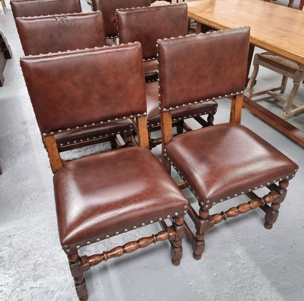 Set of eight Henry II style dining chairs including two carvers. They have leather look upholstery with brass studs. In good original condition.