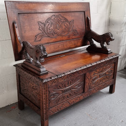 Unusual English Oak Monks Bench.  The tabletop is set onto a lift top chest in such a way that when the table is not in use, the top pivots to a vertical position and becomes the back of a Settle. Carved Lion table rests and carving to front.  In good, detailed condition.