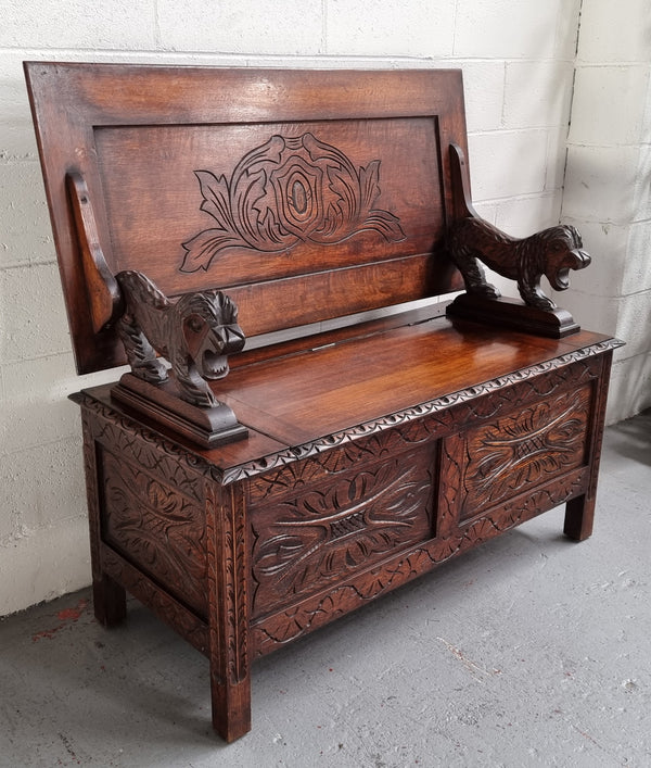 Unusual English Oak Monks Bench.  The tabletop is set onto a lift top chest in such a way that when the table is not in use, the top pivots to a vertical position and becomes the back of a Settle. Carved Lion table rests and carving to front.  In good, detailed condition.