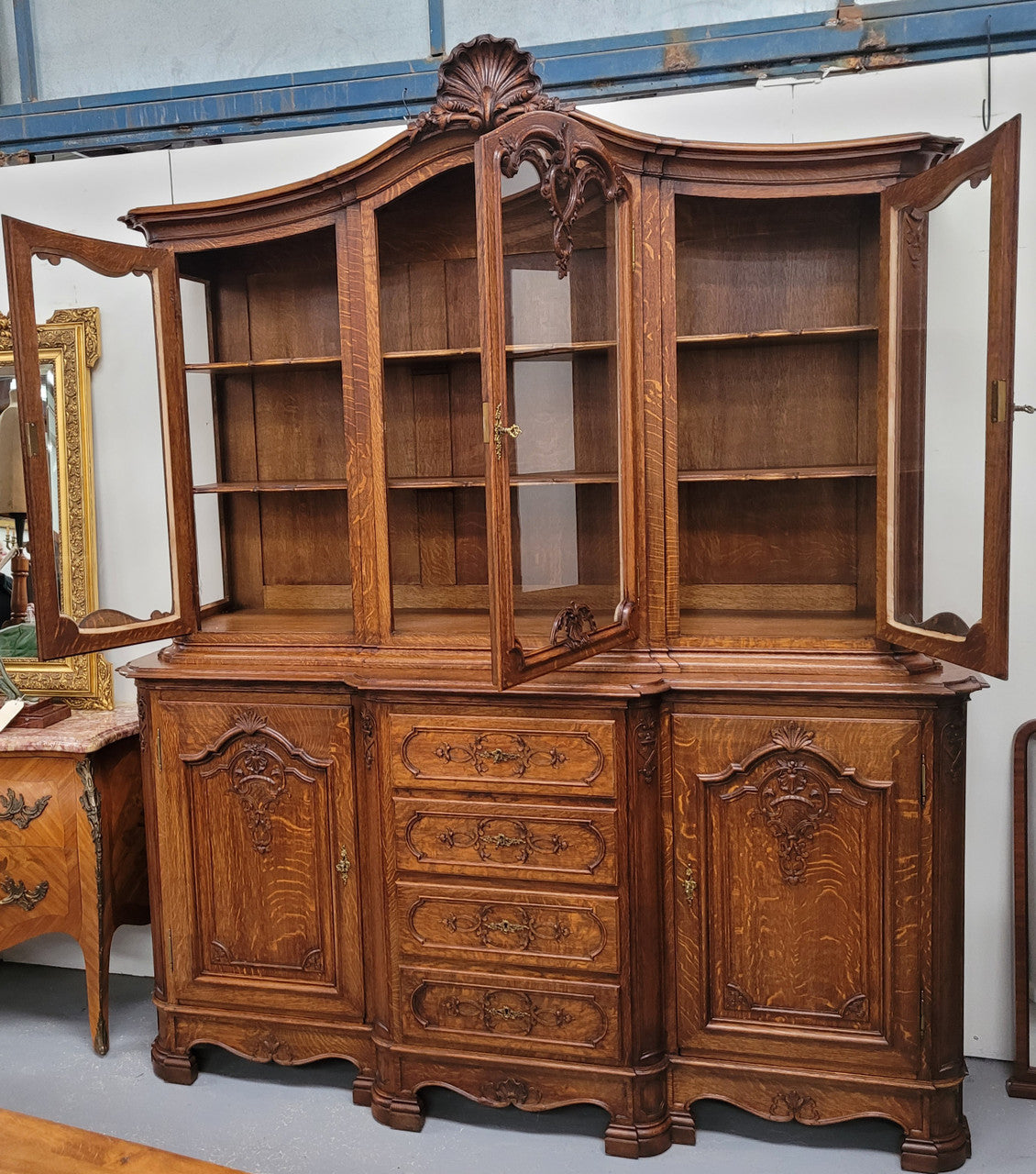 Impressive French Oak Louis 14th Style Display and Sideboard. It has 4 drawers, 2 bottom cupboards with 6 total shelves and 3 display doors with 3 shelves.  In good, detailed condition.
