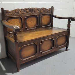 English Oak Tudor style hall seat with lift up top and a storage compartment underneath. It is in good original detailed condition with its original finish.