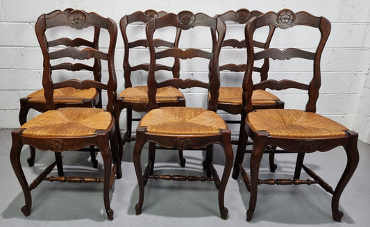Set of six French dark Oak rush seat dining chairs with ladder back. They are in good detailed original condition and very comfortable to sit in.
