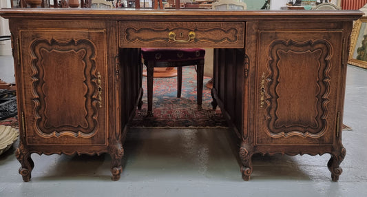 Fabulous Louis XV style French Oak beautifully carved full partners desk with an amazing tooled leather top. Both sides have a functioning drawer in the middle and two cupboards either side. On both sides one cupboard door opens up to four smaller internal drawers. Plenty of storage space and a large top surface to work on. It is in good original detailed condition.