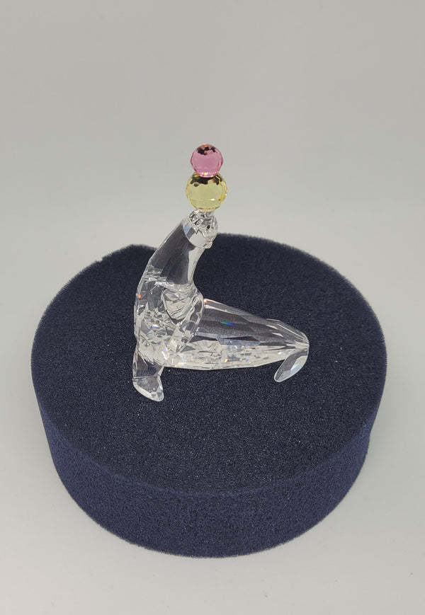 Swarovski crystal juggling seal. Jet eyes and balancing pink & yellow balls. Introduced 2003 and retired 2007.  Comes with original box.