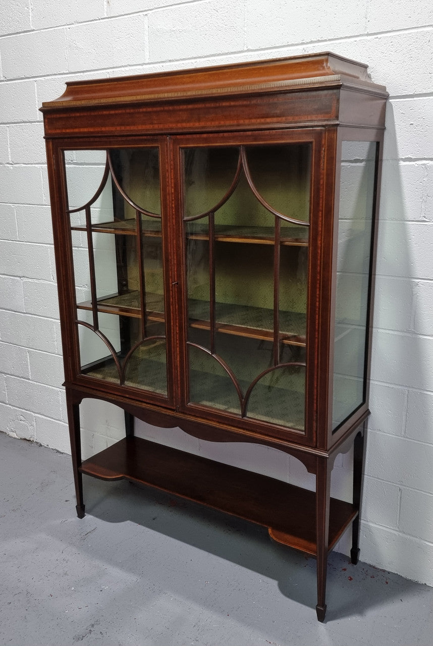 Edwardian Sheraton Revival Mahogany display cabinet with green upholstered  fabric backing and shelving with inlay and two decorative glazed doors.