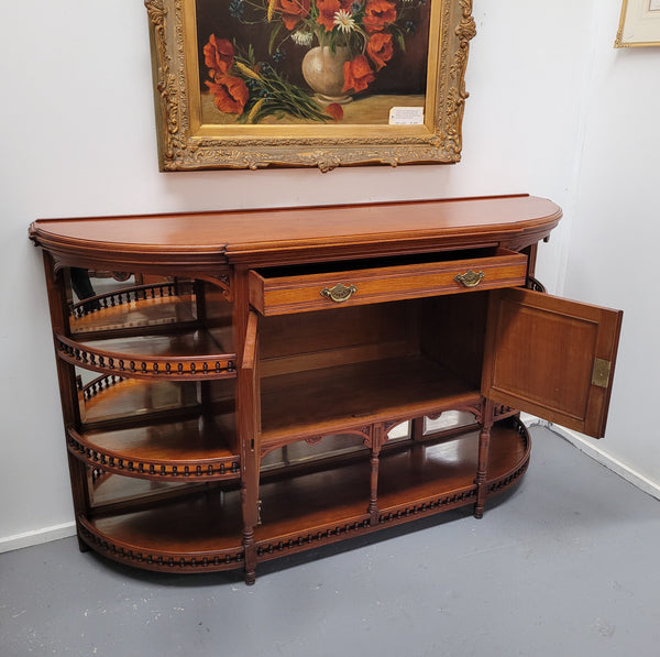 A high quality Antique Walnut sideboard featuring two mirrored doors, two drawers and five open shelf ideas with mirror backing. It is in good original detailed condition.